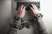 man bound in chains on a laptop computer 