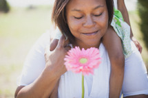 Woman with a flower carrying her daughter on her shoulders.