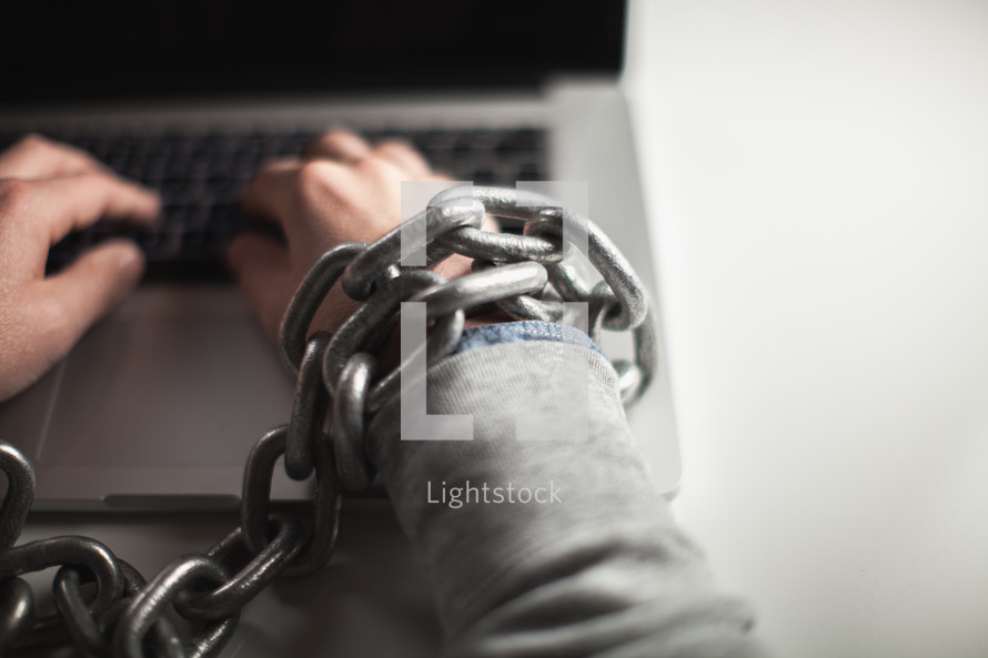 man bound in chains on a laptop keyboard 