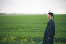 Graduate holding a Bible in a field of green grass.