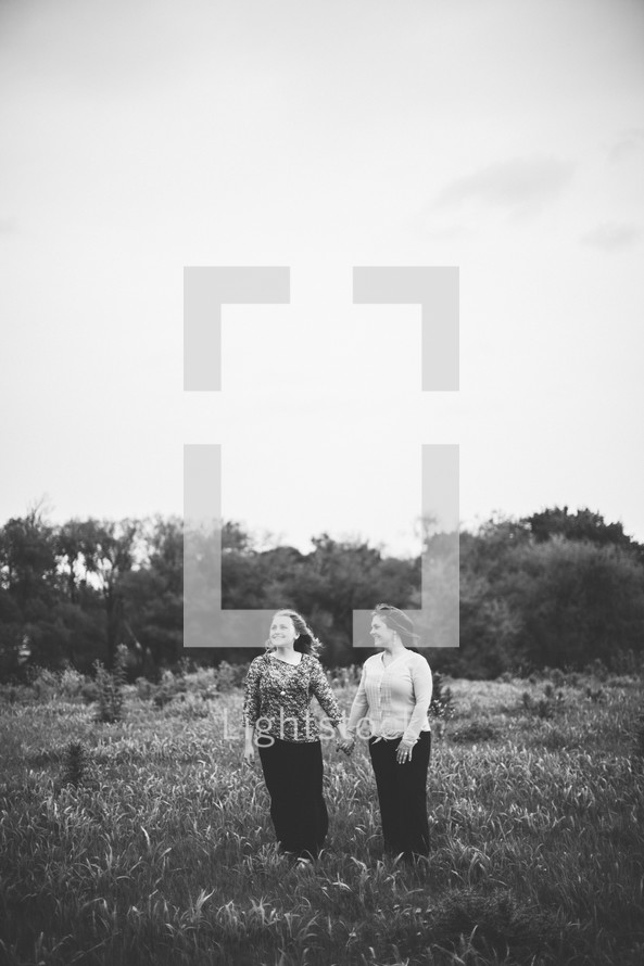 two women holding hands in a field