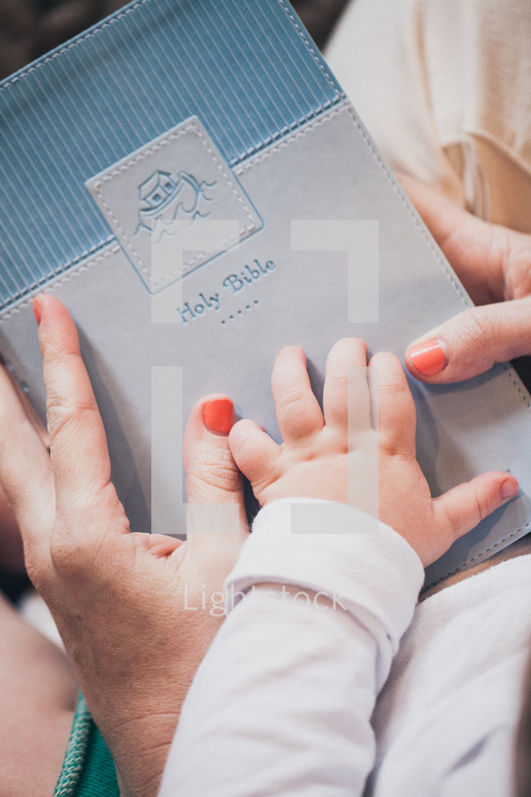 mother and infants hand on a Bible