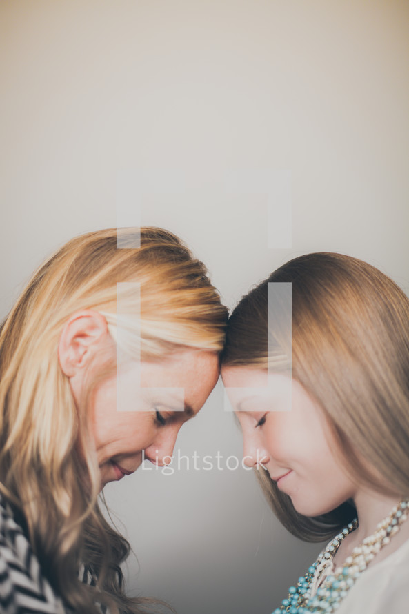 mother and daughter with heads bowed in prayer 