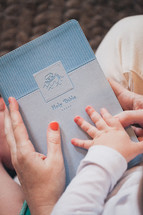 mother and son's hands on a Bible
