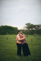 Mother and daughter embracing in a field.