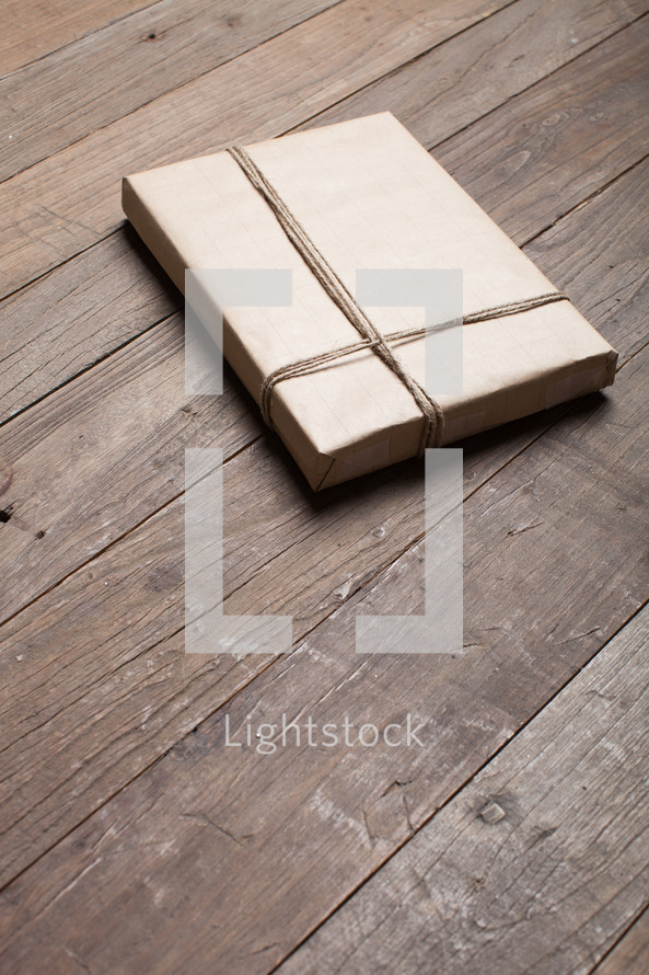 gift wrapped in brown paper on a wood floor 