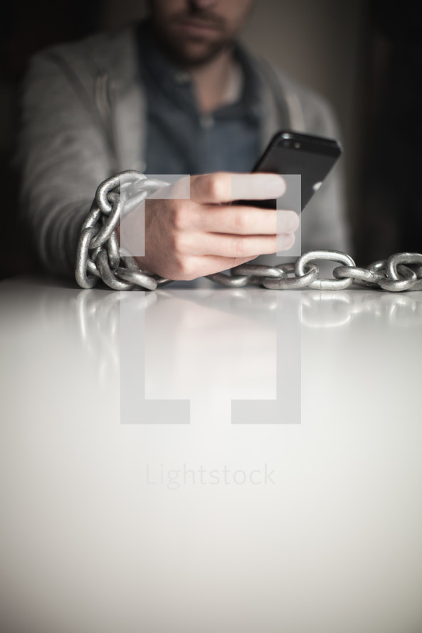 man bound in chains on a cellphone 