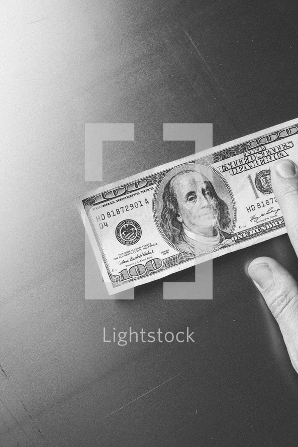 Hand touching $100 bill.