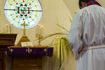 A pastor bows his head before a church altar.