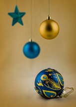 Blue and gold Christmas ornaments on a gold background.