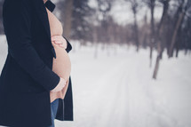 pregnant woman standing in the snow 