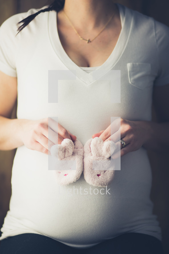 Expecting mother holding a pair of baby booties.
