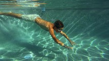 Underwater shot of boy swimming to steps in the pool