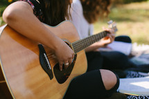 teen girl playing a guitar outdoors 
