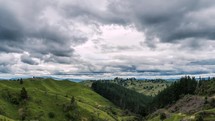 Grey clouds sky move fast over green country in New Zealand mountains nature Time lapse

