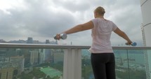 Woman doing shoulder exercises on the balcony 
