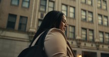 Young business woman walking around the city using her phone and laptop