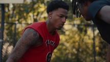 Young men playing basketball on an outdoor court on a sunny day