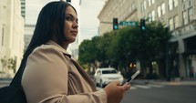 Young business woman walking around the city using her phone and laptop