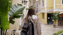 A woman walks along a city street with backpack, a tourist looks at the sights of the city.