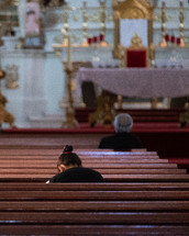 people sitting in church pews praying 