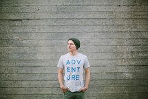 man standing outdoors wearing a t-shirt with the word adventure on it