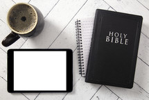 coffee cup, tablet, notebook, and Bible on a white wood background  