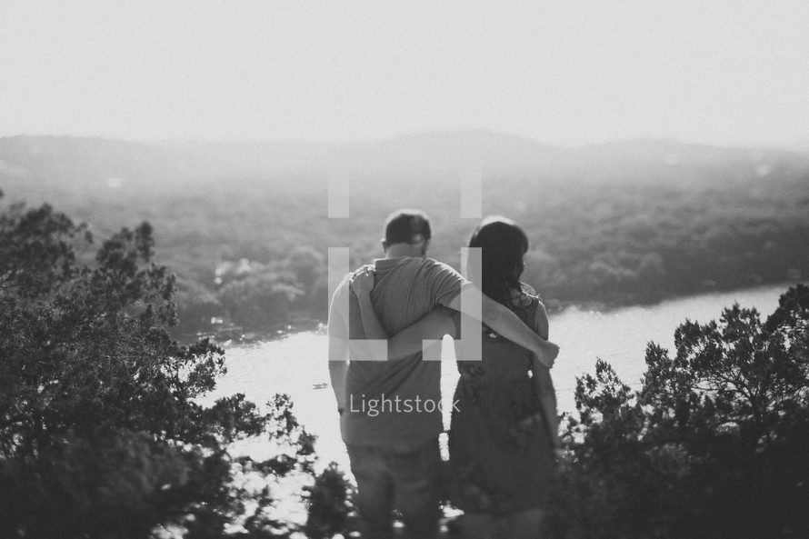 couple holding each other enjoying a view of a river