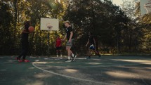 Young men playing basketball on an outdoor court on a sunny day