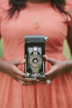 Woman's hands holding an antique camera.
