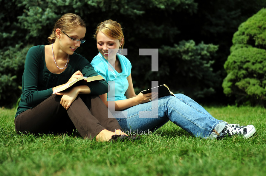 sisters reading Bibles together outdoors 
