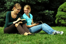 sisters reading Bibles together outdoors 