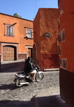 a man on a motorcycle on a cobblestone street 