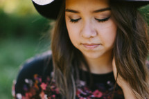 portrait of a teen girl in a hat standing outdoors 
