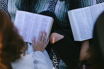 young women reading Bibles while sitting on a blanket outdoors 