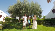 Young family with two children near olive tree in the garden