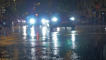 Cars with bright headlights beam driving in city at rainy
