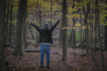 a man standing in a forest with arms raised 