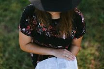 a woman in a hat reading a Bible 