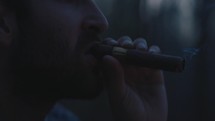 Man lighting and smoking a cigar outside during dusk