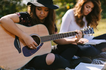 young women playing a guitar and singing 