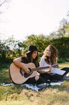 playing guitar, reading, blanket, Bible, young woman, girl, woman, sitting, outdoors