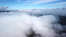 Foggy fog blows over spruce forests. Aerial shots of spruce forests on mountain hills during a foggy day. Low and central clouds in the morning.Drone view, bird’s eye view, real time footage