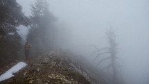 person hiking a foggy mountainside forest