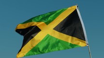 Waving Jamaica Flag On The Beach Near Ocean