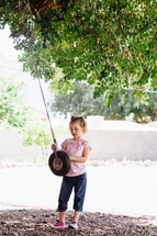 a girl child playing with a tire swing 