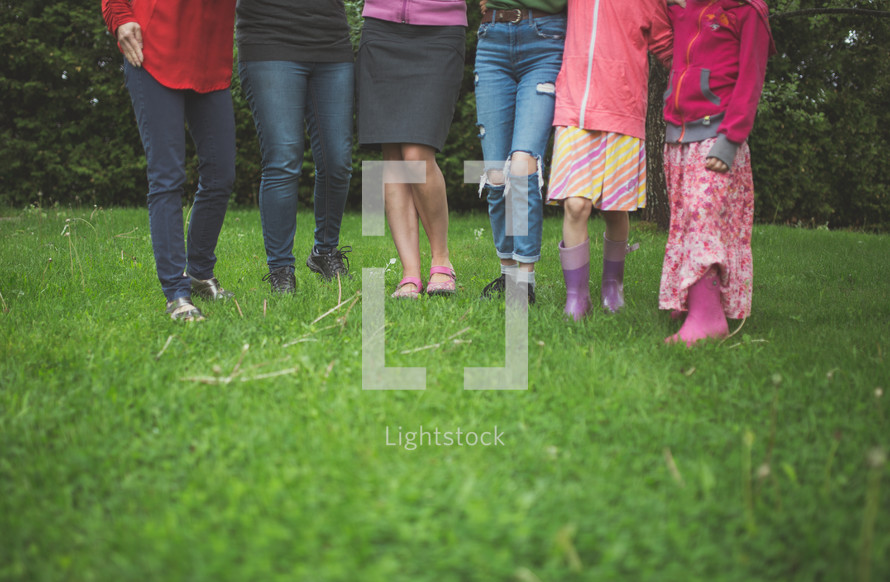 legs of girls standing in grass 