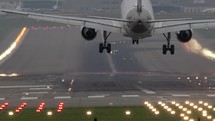 Slow motion video from behind a commercial airplane as it lands on a runway.