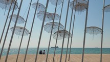Couple on waterfront with Umbrellas sculpture 