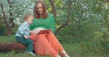 Pregnant mother and son with tablet PC outdoor